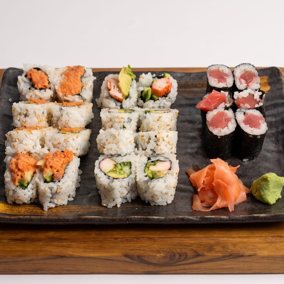 Assorted sushi rolls, including spicy tuna, California, and tuna maki, with ginger and wasabi.