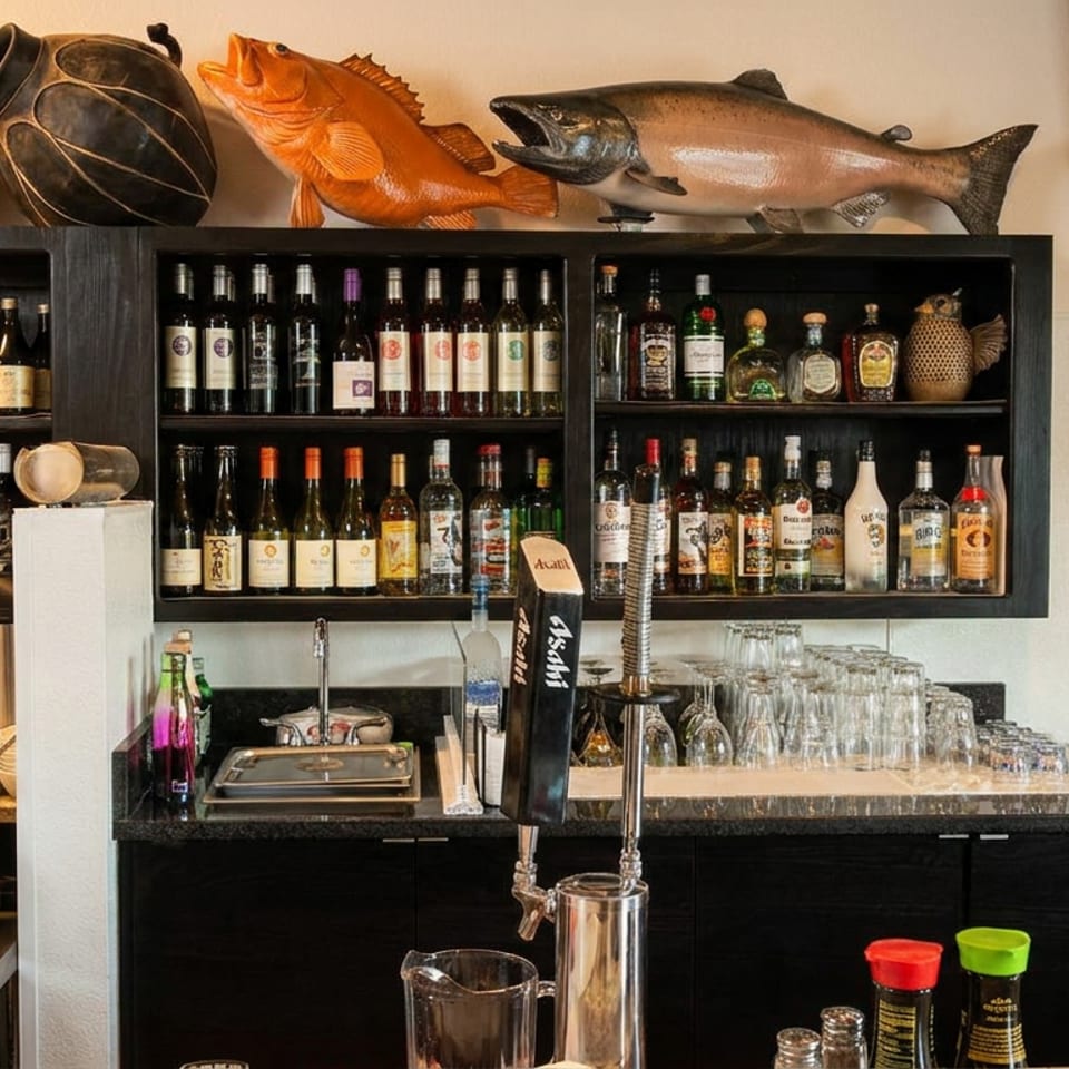 Restaurant bar area with shelves of wine and liquor bottles, beer taps, and kitchen equipment.